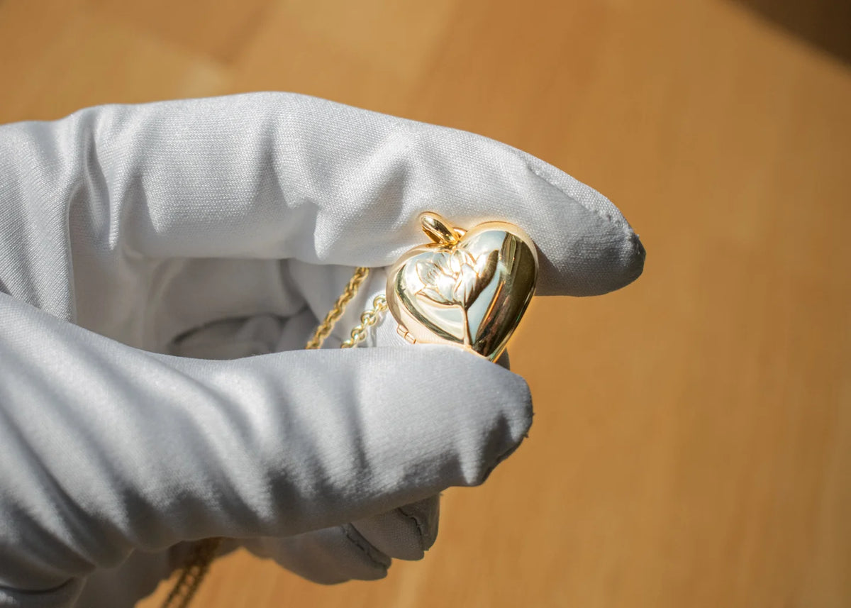 Hjerteformet mindemedaljon vist på en hvid handske