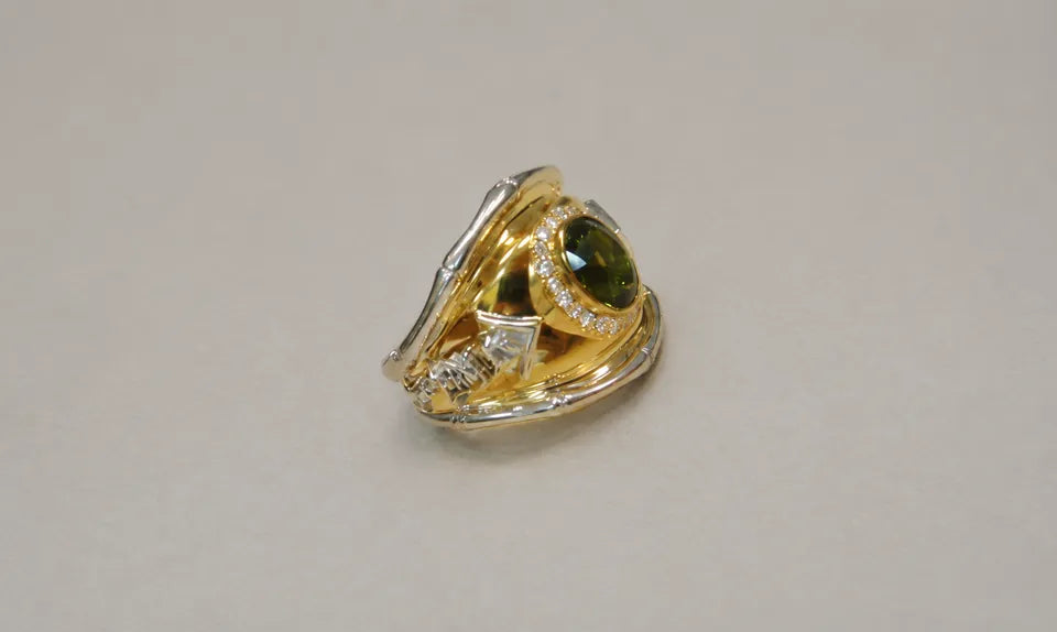 Aikido-ring i gult guld med oval grøn turmalin og lyse detaljer