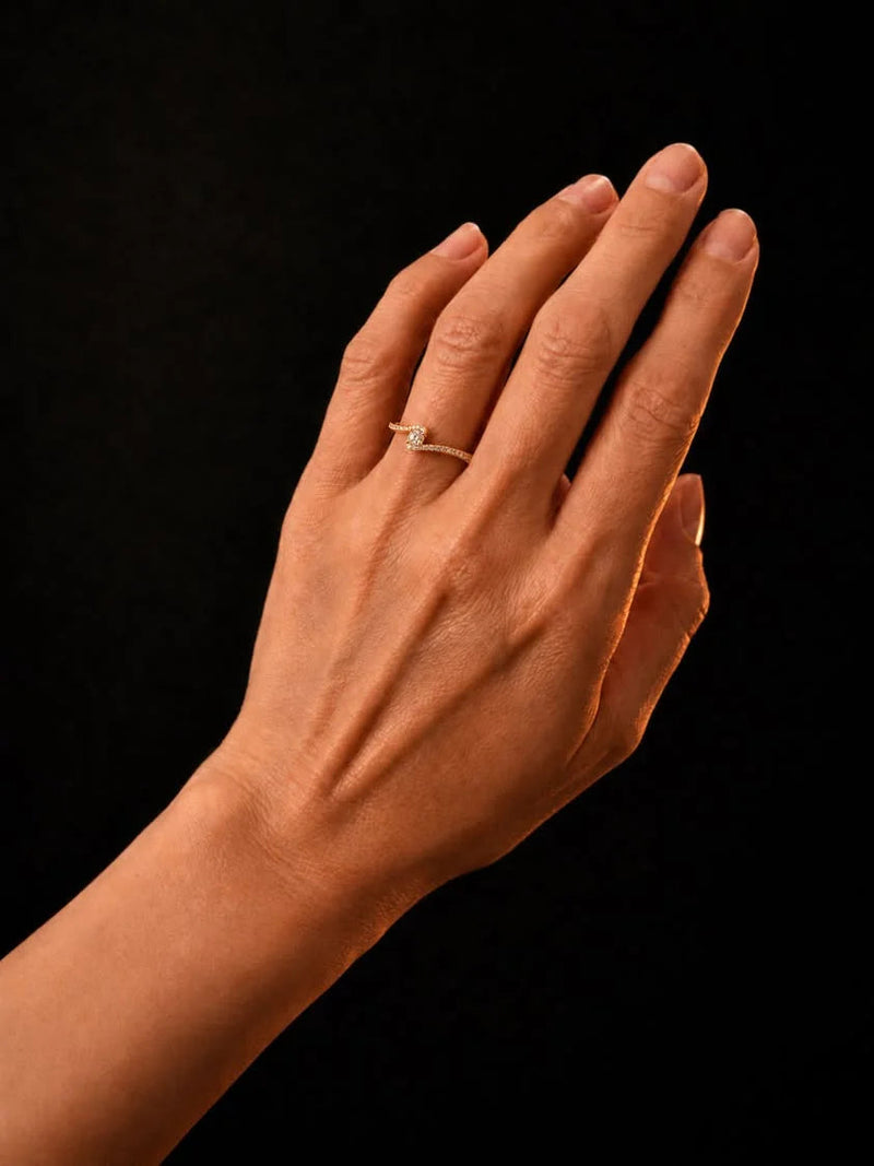 Forlovelsesring med diamanter og en svungen ringskinne, vist på en hånd