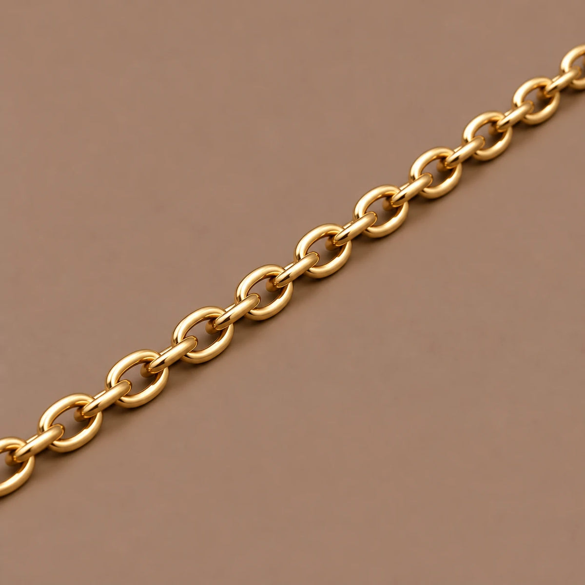 Ankerkæde i 18 kt gult guld, 2,5 mm, med ovale led på taupe baggrund.