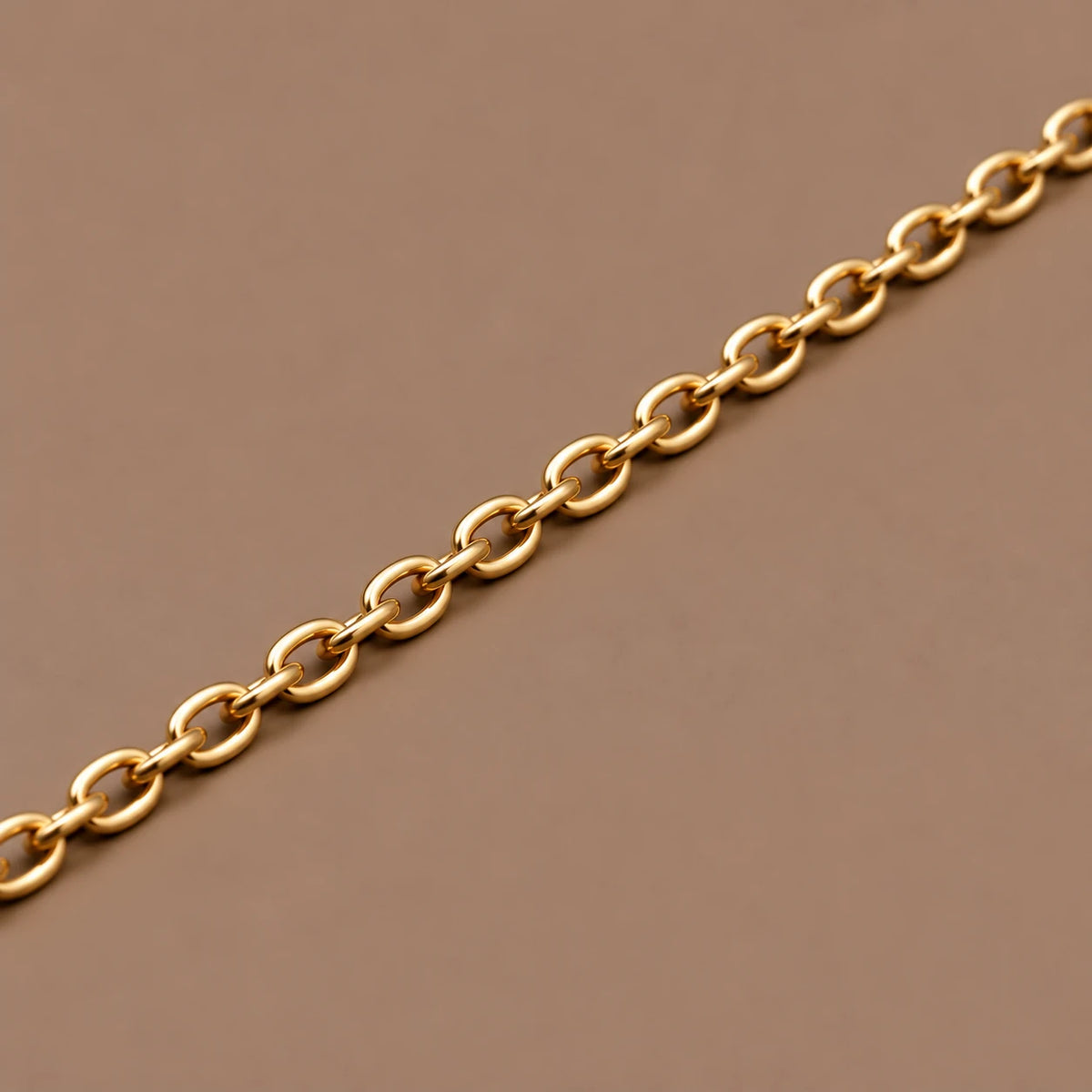 Ankerkæde i 18 kt gult guld, 2 mm, med ovale led på taupe baggrund.