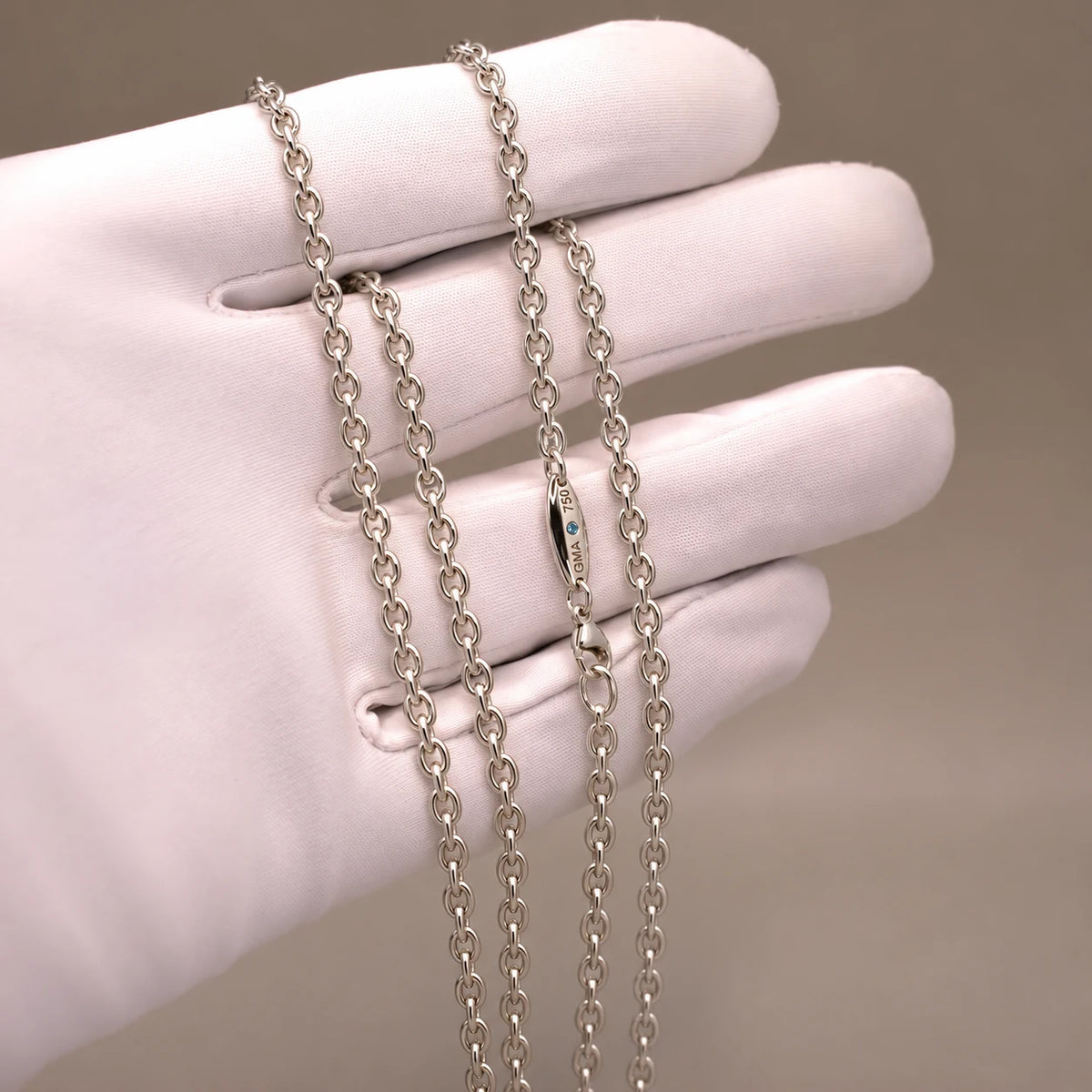 Ankerkæde i 18 kt hvidguld, 2,6 mm, på hvid handske med blå diamant ved låsen.