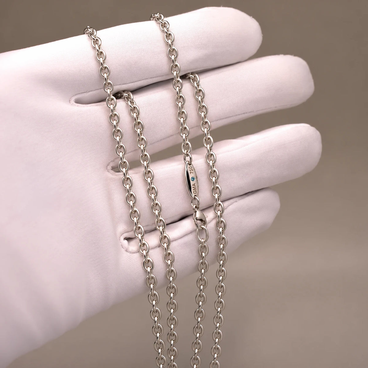 Ankerkæde i 18 kt hvidguld, 3 mm, på hvid handske med blå diamant ved låsen.