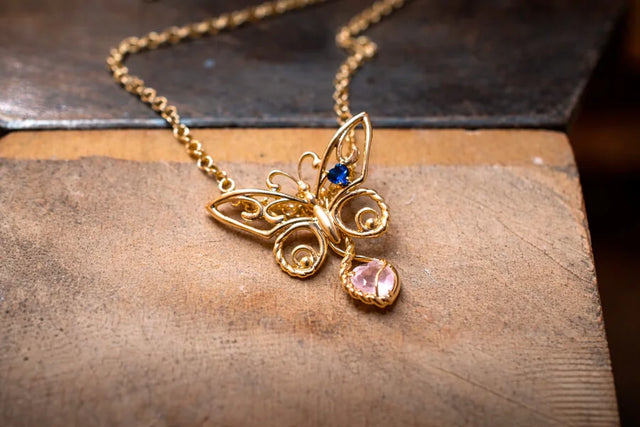 Sommerfuglevedhæng med blå safir og et ekstra vedhæng med en rosa hjerteformet sten