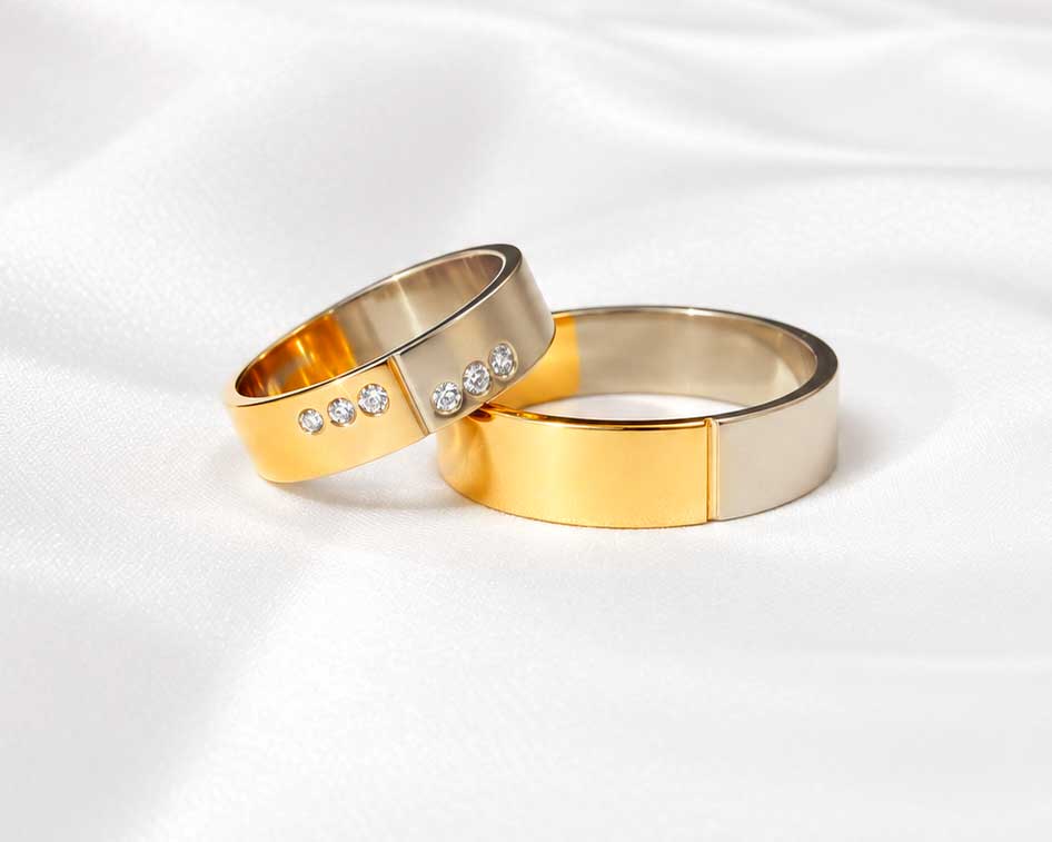Vielsesringe i hvidguld og gult guld med blanke flader og diamanter i hendes ring