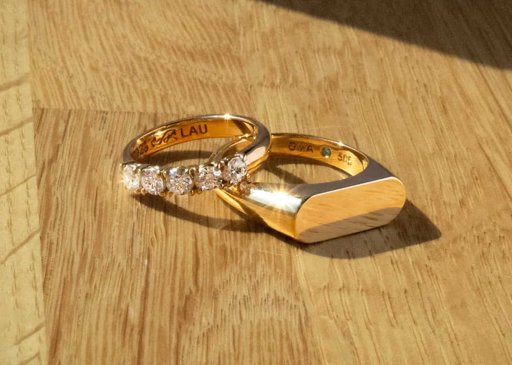 To vielsesringe i gult guld, en ring med fem diamanter og en bred ring med blank signetform
