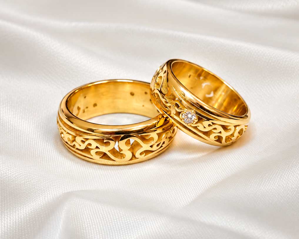 Vielsesringe i guld med gennembrudte, slyngede ornamenter og en diamant i hendes ring