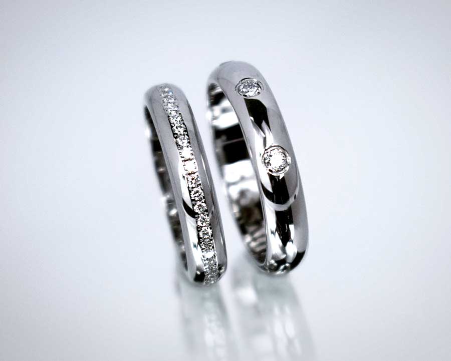 To vielsesringe i hvidguld, hendes med mange små diamanter og hans med færre større diamanter