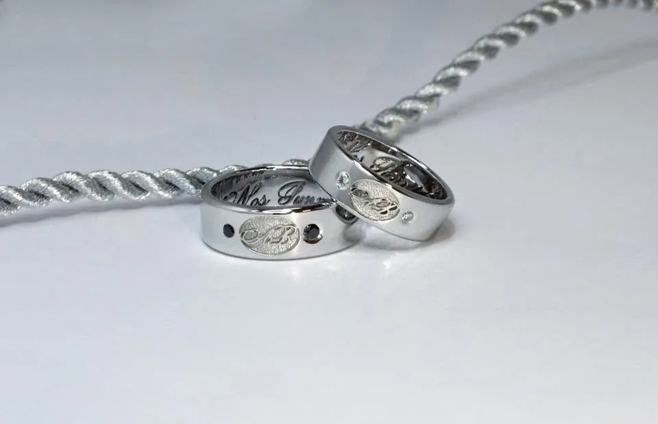 Vielsesringe med initialer, indvendig gravering og en sort diamant i hans ring og en hvid diamant i hendes