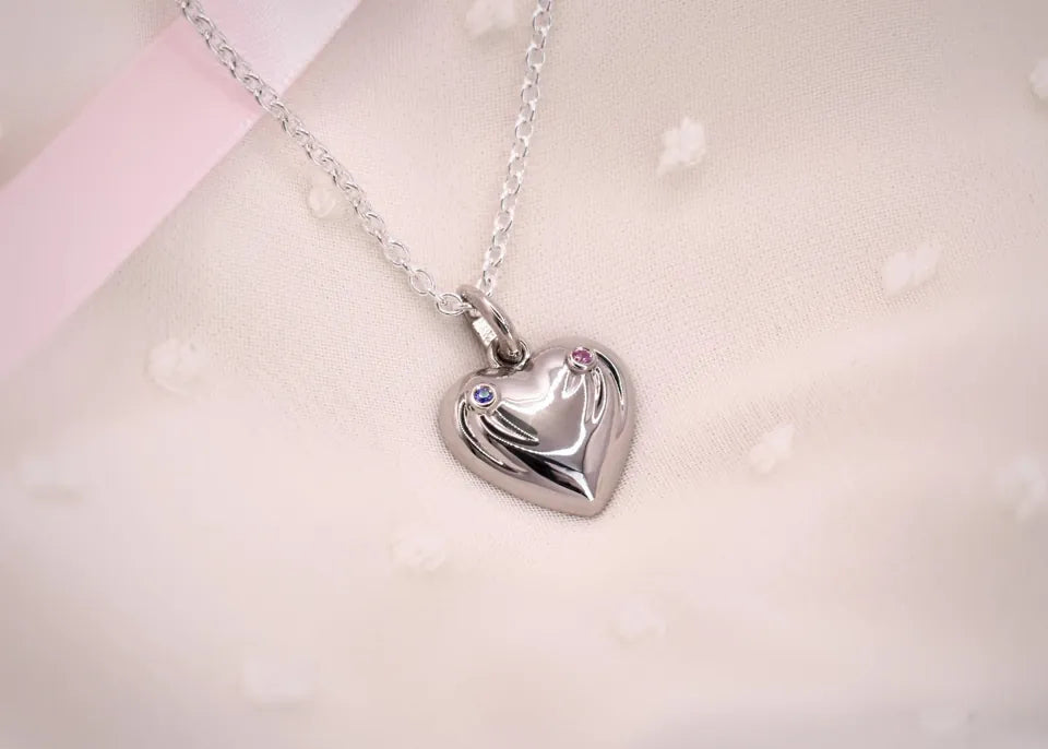 Hjertevedhæng i hvidguld med en blå og en lyserød safir og linjer, der symboliserer familiens børnebørn
