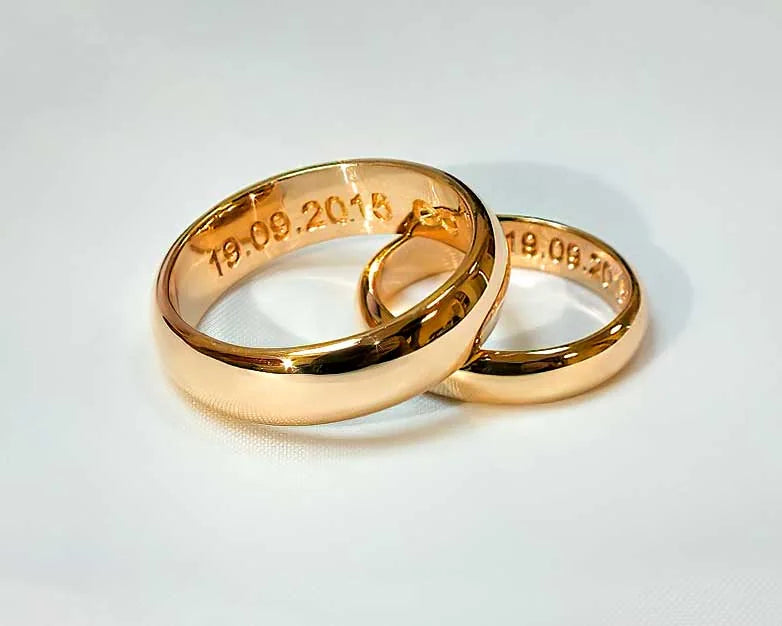 Klassiske vielsesringe i guld med blanke overflader, forskellig bredde og bryllupsdato på indersiden