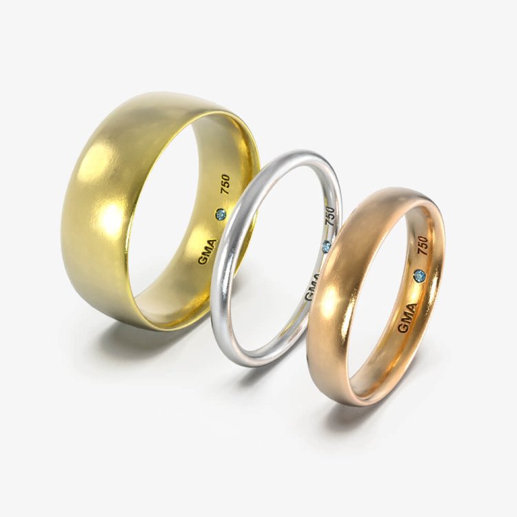 Tre vielsesringe med rund profil i gult, hvidt og rosafarvet guld, med navnestempel og blå diamant indvendigt