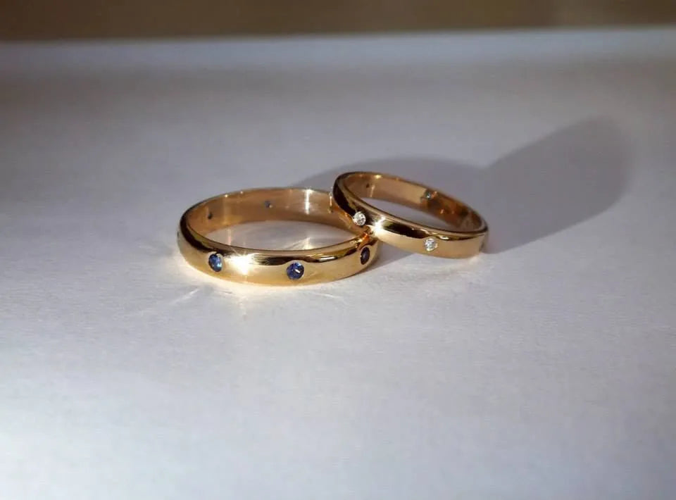 Klassiske vielsesringe i guld med safirer i hans ring og diamanter i hendes, i lukkede fatninger